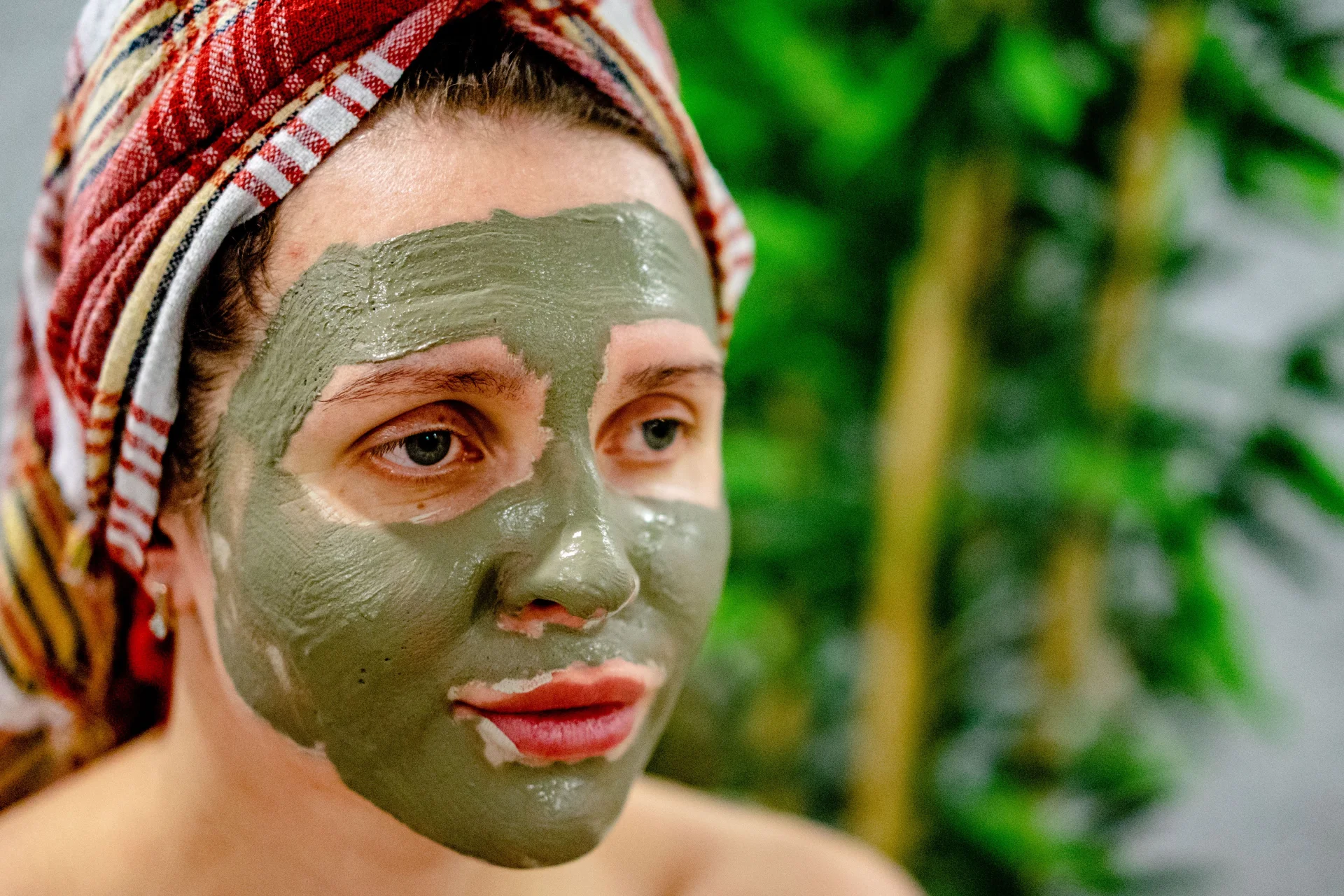 Kobieta z maseczką błotną na twarzy, relaksująca się podczas zabiegu spa.